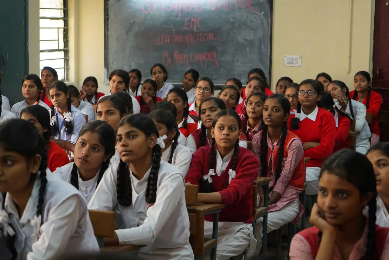 Schoolgirls in uniform sitting together and listening in a classroom